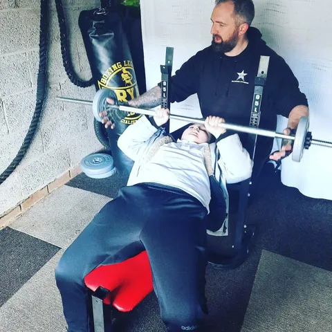Wayne coaching a client through a bench-press set in the gym